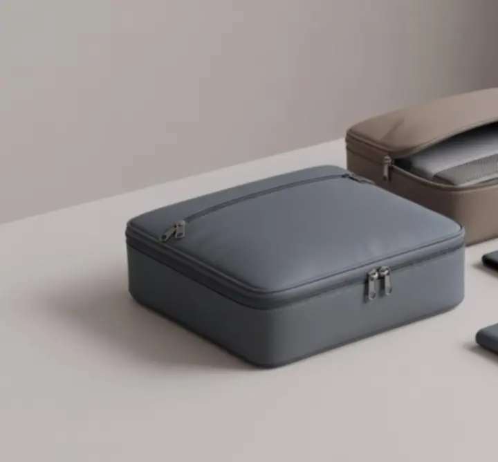 Zestaw eleganckich organizerów podróżnych i kostek do pakowania Pack Organize ułożonych obok walizki.